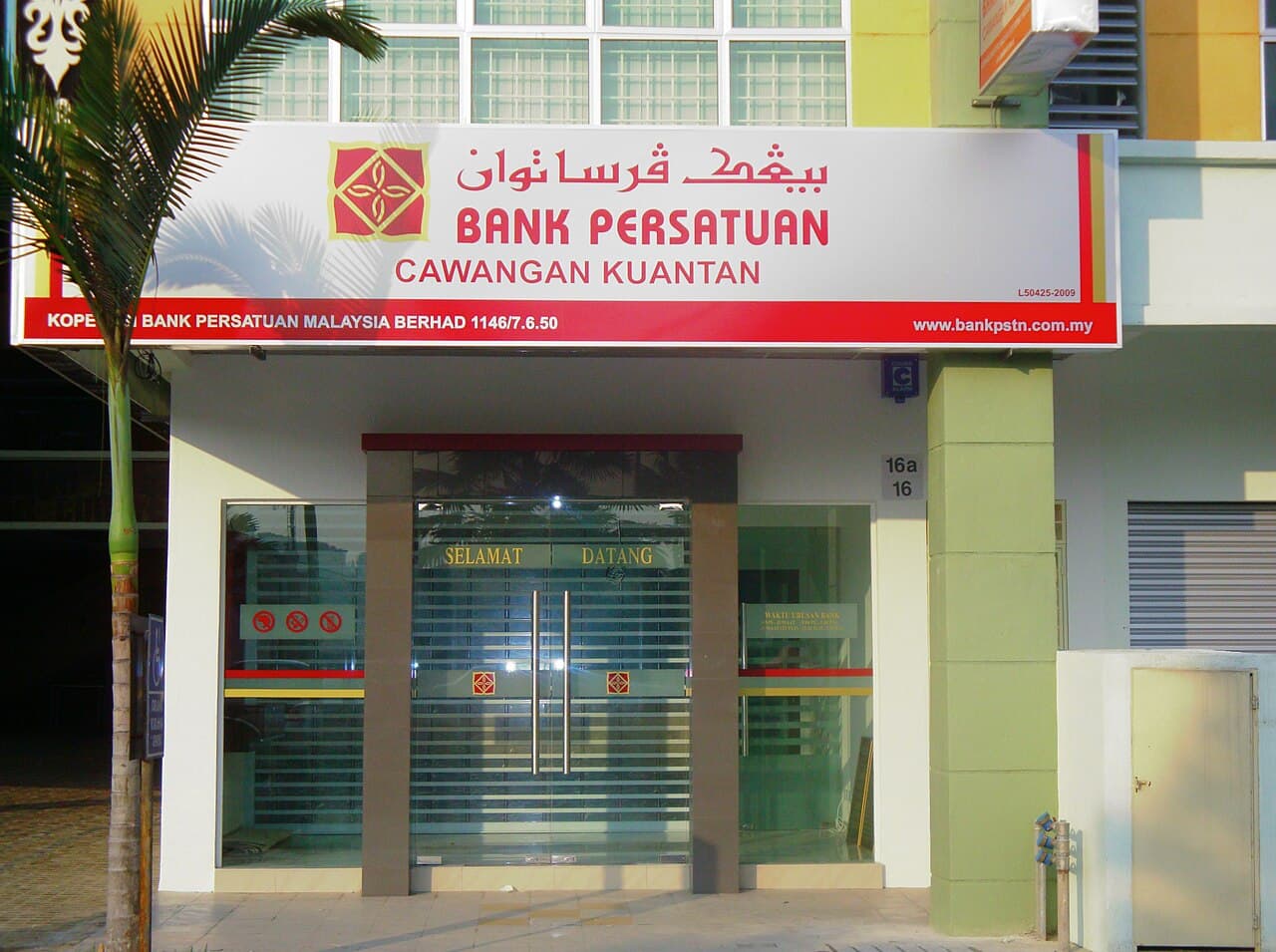 The Kuantan branch of Bank Persatuan in Malaysia — the glass shopfront of the co-operative bank Koperasi Bank Persatuan Malaysia Berhad, its red-and-white signboard with the cooperative's diamond emblem above the entrance and a 'Selamat Datang' welcome on the doors